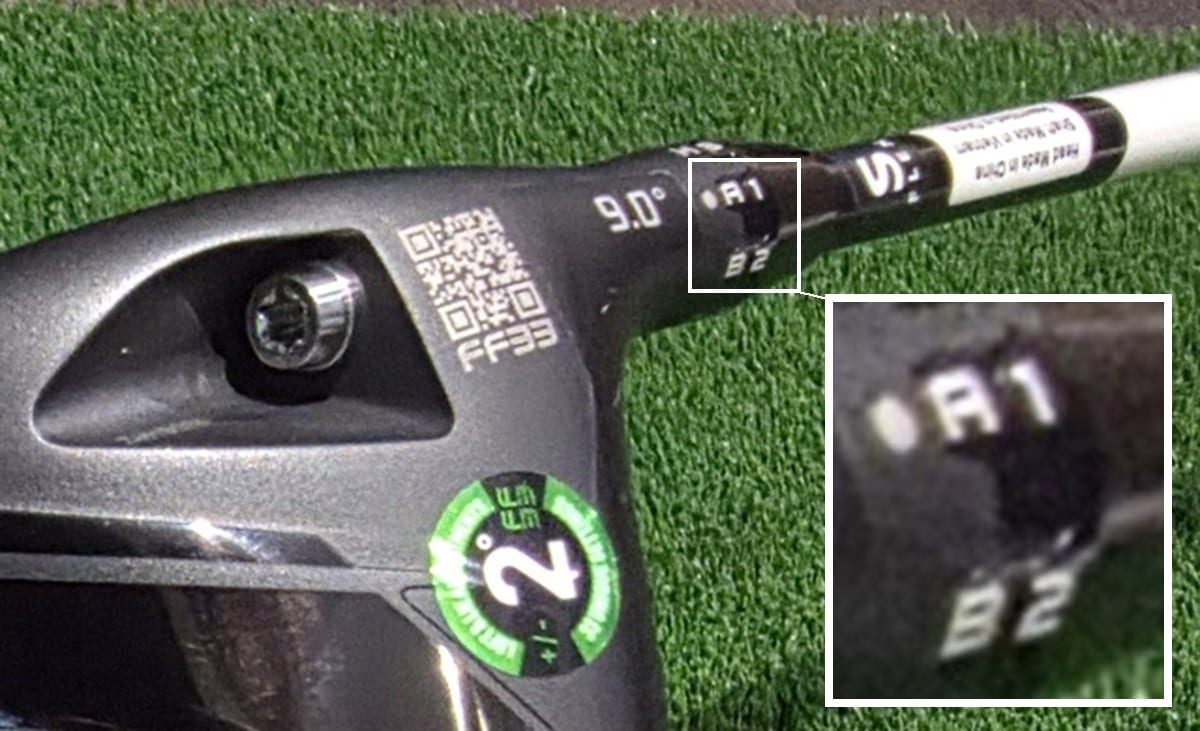Close-up of the hosel on the author's Cobra DS-ADAPT driver lying on artificial turf, showing a QR code, an FF33 stamp and a 9.0 degree loft stamp on the head. A boxed inset at lower right magnifies the sleeve, where the code A1 sits above the code B2.