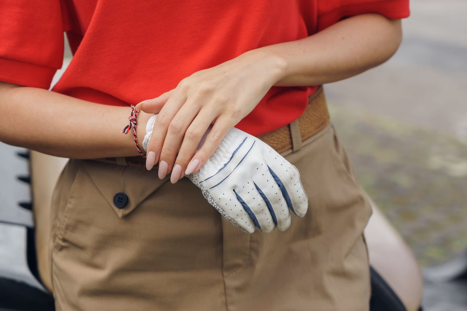 A golfer smoothing a white golf glove over her fingers.