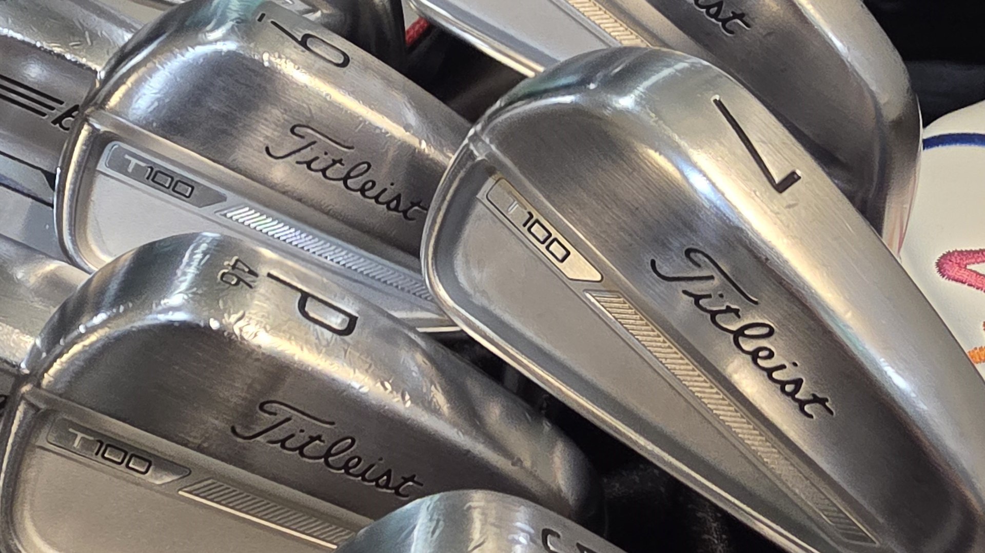 Close-up of the author's Titleist T100 iron heads stacked in a golf bag, with the 46-degree pitching wedge visible.