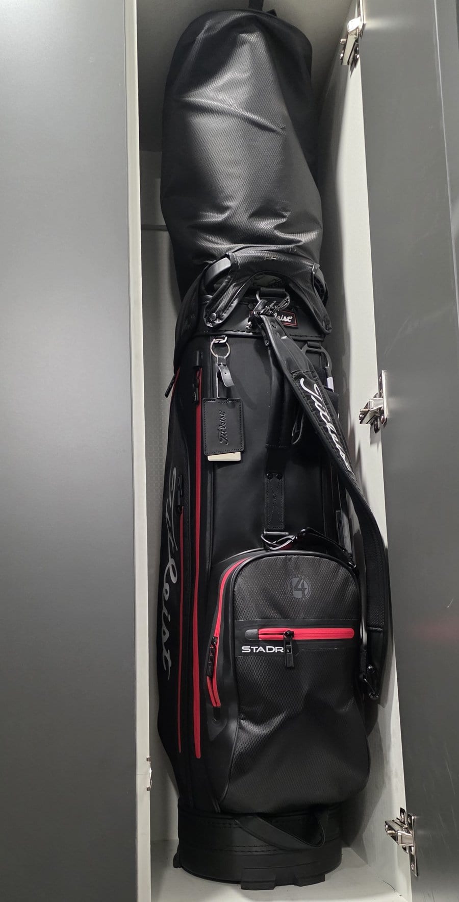 The author's golf bag standing upright in a clubhouse locker, with a rain hood pulled over the top so none of the club heads show.