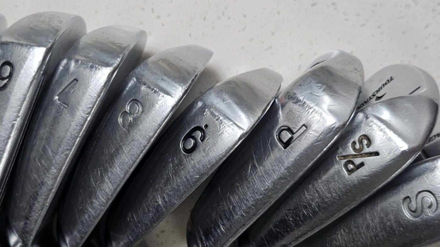 Tourstage V300 III irons lined up on a counter, soles toward the camera, with the stamps 6, 7, 8, 9, P, P slash S and S readable along the row.