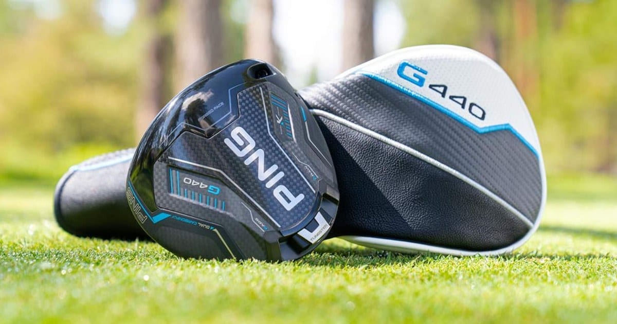 A PING G440 driver head on grass with the sole facing the camera, next to a white, black and light blue G440 headcover.