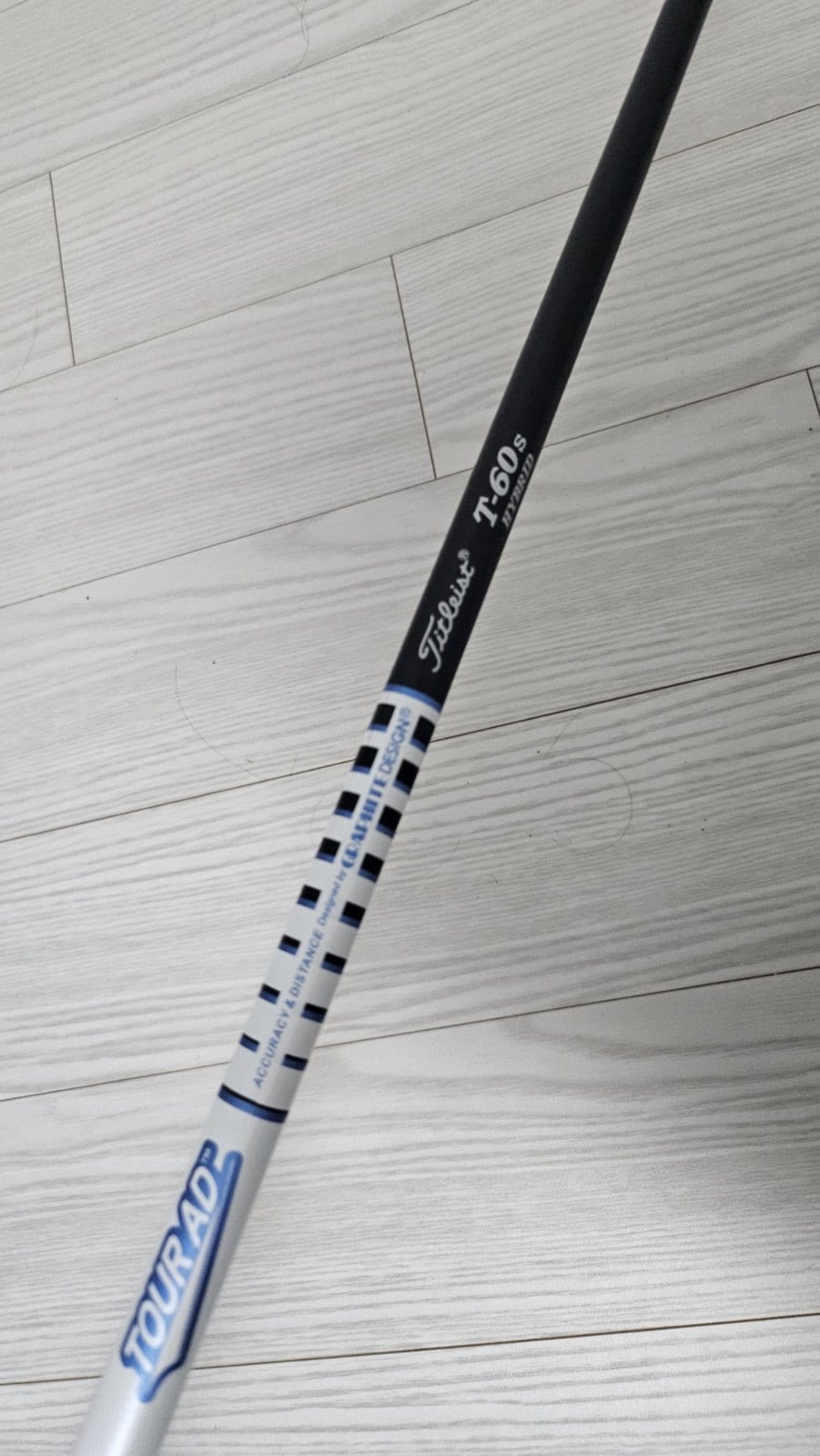 A golf shaft band photographed at an angle, reading Titleist T-60 S HYBRID above a white section printed TOUR AD, accuracy and distance, designed by Graphite Design.
