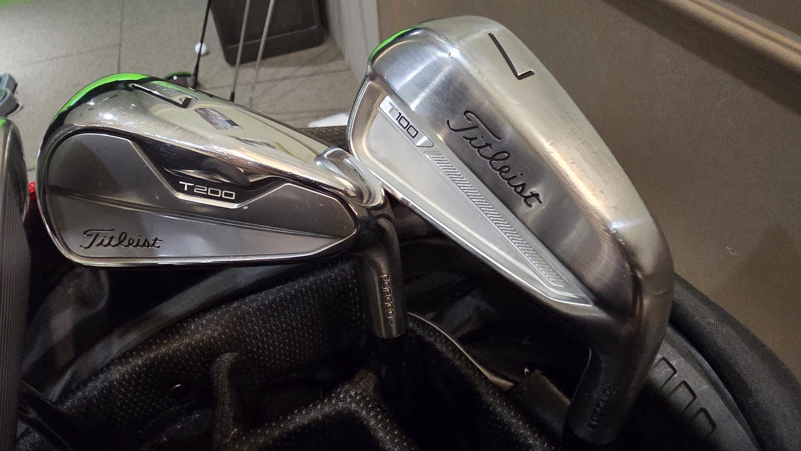 A friend's Titleist T200 7-iron beside the author's T100 7-iron, showing the difference in head size and topline.
