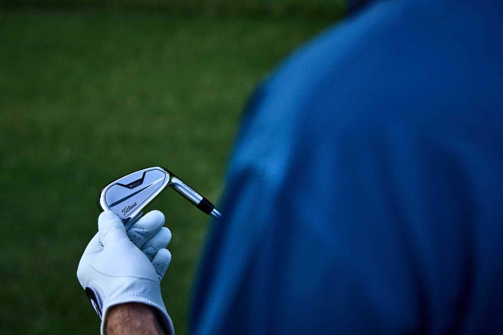 A 2021 Titleist T200 iron held up from behind, showing the muscle plate across the back of the head.