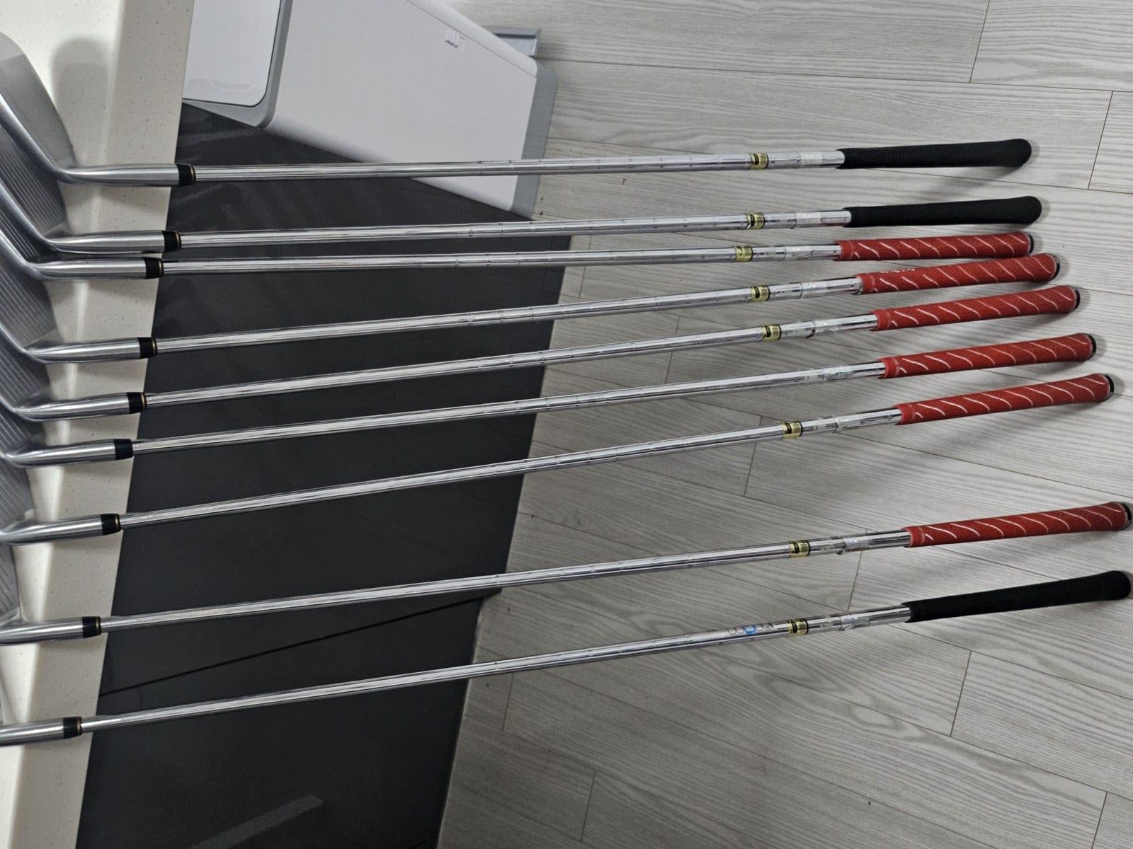 Nine Tourstage V300 III irons laid out with shafts and grips visible, four iron through sand wedge.