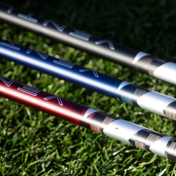 Three Fujikura Ventus TR shafts in gray, blue, and red laid across grass, each showing the VENTUS wordmark on the band.