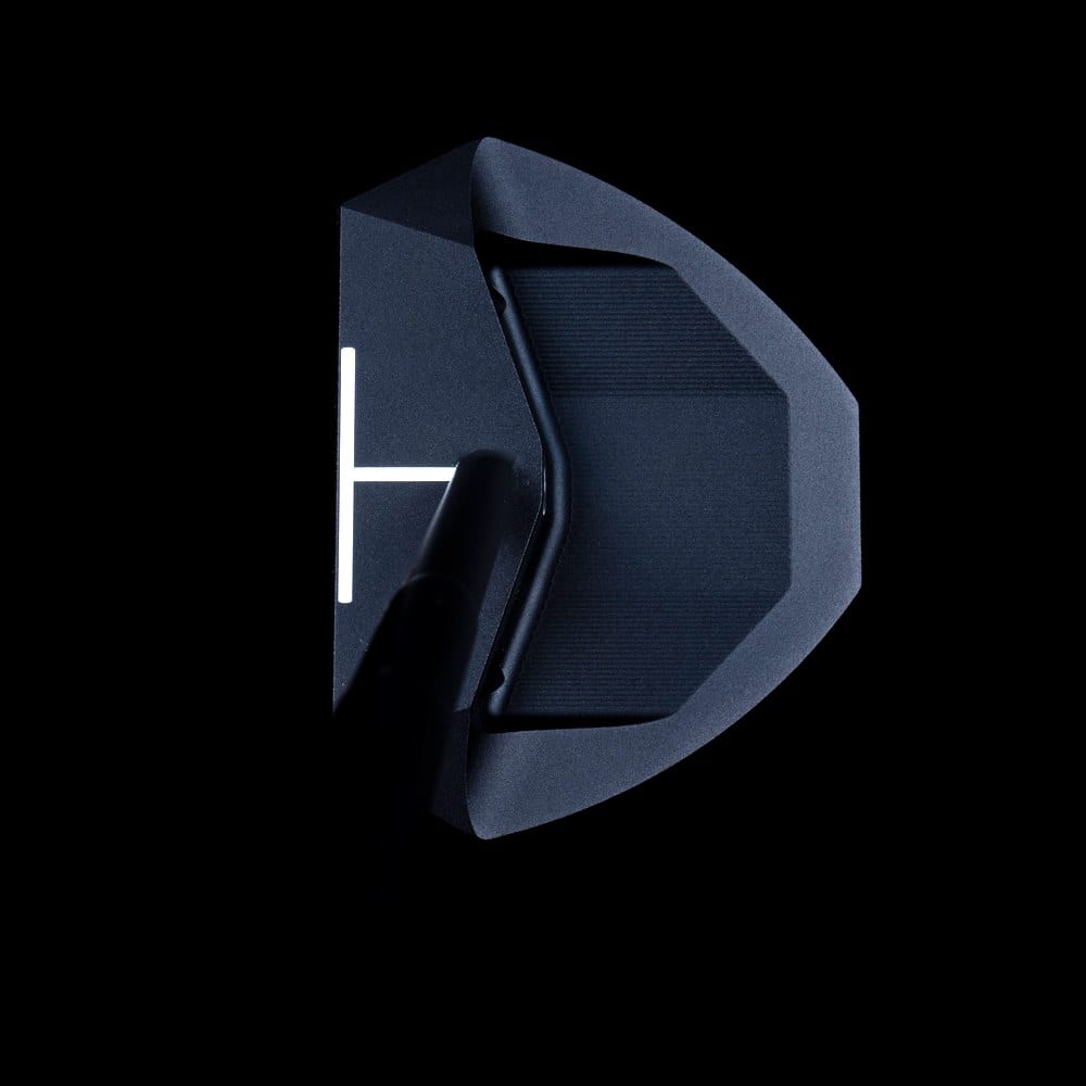 The L.A.B. Golf OZ.1i seen from address against a black background, a wide mallet body with a white alignment mark near the face and the shaft bending once and meeting the head around the middle of the face.